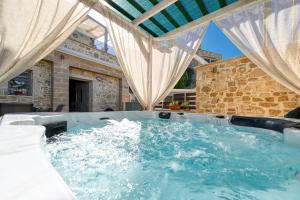a hot tub in a patio with curtains at Petros Luxury Traditional House - Villa in Kissamos
