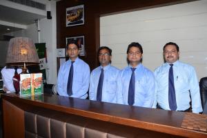un grupo de hombres de corbatas parados detrás de un mostrador en Green Hotel & Restaurant, en Pathankot