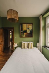 een groene slaapkamer met een groot bed met 2 kussens bij Maison Comtale in Rochefort