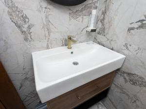 a white sink in a bathroom with marble walls at Hotel RAS Pazarište in Novi Pazar