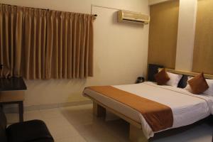 a hotel room with a bed and a window at Cool Palace Hotels in Nashik