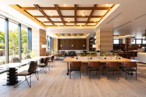 un comedor con mesas, sillas y ventanas en AQA Hotel Premium en Saku