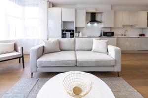 a living room with a couch and a kitchen at Ealing Residency in London