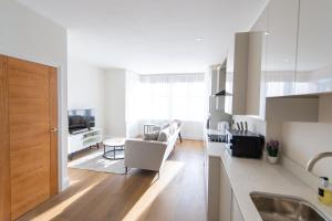 cocina y sala de estar con sofá y mesa en Ealing Residency, en Londres