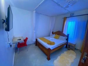 - une chambre avec un lit, une télévision et une chaise rouge dans l'établissement Mtwapa Texas Villa Guest House, à Mtwapa