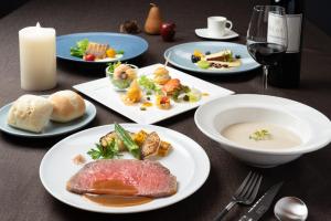 a table with plates of food and a glass of wine at AQA Hotel Premium in Saku