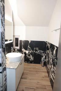 La salle de bains est pourvue d'un lavabo blanc et de carrelage noir. dans l'établissement Swiss Apartmani, à Banja Luka