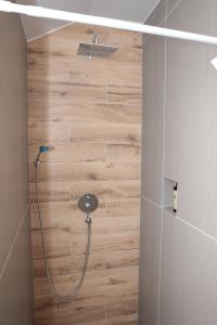 La salle de bains est pourvue d'une douche et d'un mur en bois. dans l'établissement Swiss Apartmani, à Banja Luka
