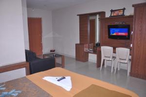 uma sala de estar com uma mesa e cadeiras e uma televisão em Mahathi Residency 