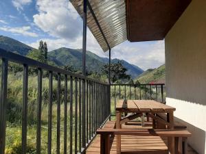 a wooden balcony with a picnic table and mountains at Kegeti Panorama Holiday Chalet in Kegeti