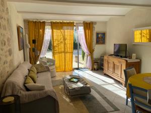 ein Wohnzimmer mit einem Sofa und einem TV in der Unterkunft LE MAS D'ISACHRIS Le T2 in La Garde-Adhémar