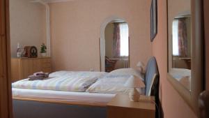 a bedroom with a bed and a table and a mirror at Pension Waldhaus in Eibenstock +11 photos