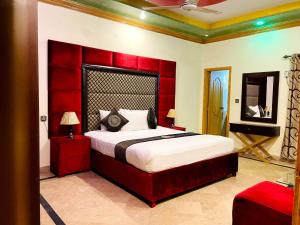 a bedroom with a large bed with a red headboard at Infinity Hotel in Lahore