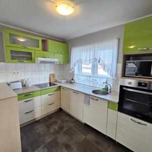 eine Küche mit grünen Schränken, einem Waschbecken und einem Fenster in der Unterkunft Guesthouse Kiljan in Blönduós