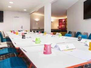 une salle de conférence avec des tables blanches et des chaises bleues dans l'établissement ibis Styles La Rochelle Centre, à La Rochelle