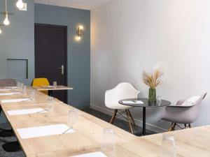 una sala de reuniones con una mesa larga y sillas en ibis Valenciennes, en Valenciennes