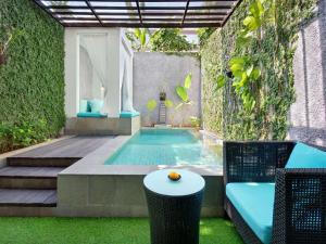 a swimming pool with a chair and a table at Mercure Bali Legian in Legian