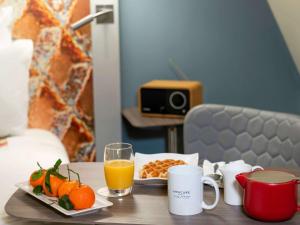 a table with a plate of fruit and a glass of orange juice at Mercure Lille Centre Vieux Lille in Lille