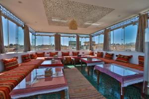 a large room with couches and tables and windows at Dar Borj in Fès