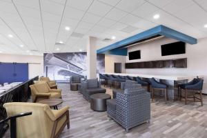 a lobby with a bar with chairs and tables at Wingate by Wyndham Wichita Airport in Wichita