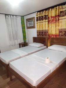 two beds in a room with curtains at Ziah's Guest House in San Vicente