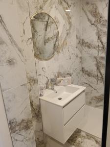 a white bathroom with a sink and a mirror at LiNZ CITY SUITE in Linz