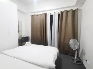 um quarto com uma cama branca e uma ventoinha em Accommodation services-anne em Manila