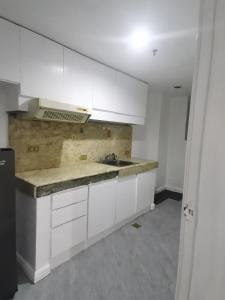 uma cozinha vazia com armários brancos e um lavatório em Accommodation services-anne em Manila