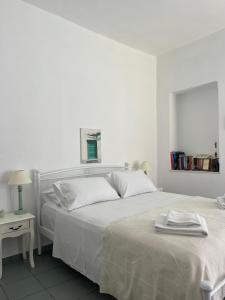 a white bedroom with a large bed with white sheets at Estia κατάλυμα στο Μύρτος in Myrtos