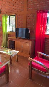 sala de estar con TV y cortinas rojas y verdes en Casa de la Luna, Juayúa., en Juayúa