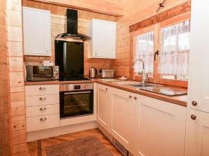 Ballinorig Lodge في Cleator Moor: مطبخ مع دواليب بيضاء ومغسلة
