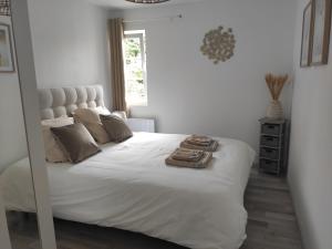 a bedroom with a large white bed with a mirror at Le Petit Gite de la Roseraie in Quiberville