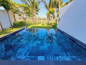 een zwembad met blauw water en palmbomen bij Sanctuary Ho Tram Villa in Ho Tram