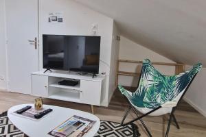 a living room with a tv and a chair and a table at Cocon sous les toits By UnSejourANancy Fr in Nancy
