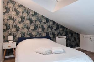 a bedroom with a bed with two towels on it at Cocon sous les toits By UnSejourANancy Fr in Nancy +17 photos