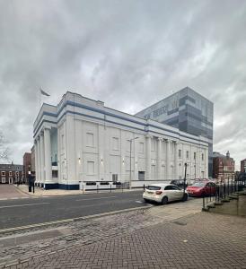 a large white building with cars parked in front of it at Cosy City Escape in Hull