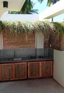a kitchen with a sink and a straw roof at Siargao Residency by Privacy Group in General Luna