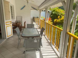 a patio with a table and chairs on a porch at Bungalow Belfond Plage Pointe Marin in Sainte-Anne