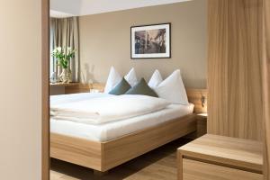 a bedroom with a bed with white sheets and pillows at Hotel Johann Lauterach in Lauterach