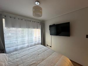 1 dormitorio con 1 cama y TV de pantalla plana en Depto Las Condes - San Pascual, en Santiago