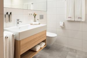 a white bathroom with a sink and a toilet at Hotel Johann Lauterach in Lauterach