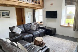 uma sala de estar com um sofá de couro e uma televisão em Close to Snowdon with Mountain views of Snowdonia em Caernarfon