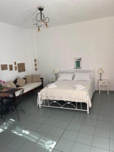 a white bedroom with a bed and a couch at Estia κατάλυμα στο Μύρτος in Myrtos