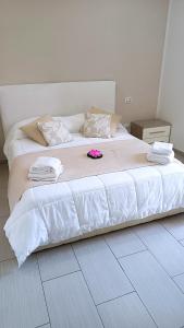 Una gran cama blanca con una flor rosa. en Casa da Sogno en Nápoles