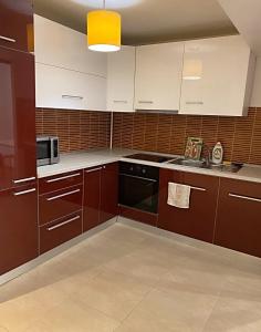 eine Küche mit braunen und weißen Schränken und einer Mikrowelle in der Unterkunft DMT Apartament regim hotelier Rin in Bukarest + 21 Fotos