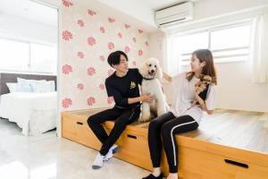 een man en een vrouw op een bed met een hond bij Guest room WES - Vacation STAY 49860v in Uruma