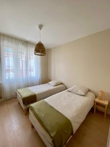 1 dormitorio con 2 camas y ventana en Appartement "Escapade à Malo"pour 4 à 6 personnes 5 mn de la plage en Dunkerque