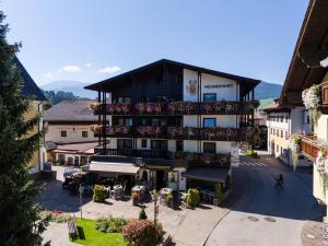 an apartment building with a balcony with tables and chairs at Hotel Mesnerwirt in Westendorf