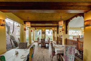 焦特布尔Surpura Bagh - A Luxury Boutique Resort的有桌椅和窗户的餐厅