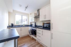 uma cozinha com armários brancos e um balcão preto em Lovely Studio Flat in Wimbledon w/ Free Parking em Londres